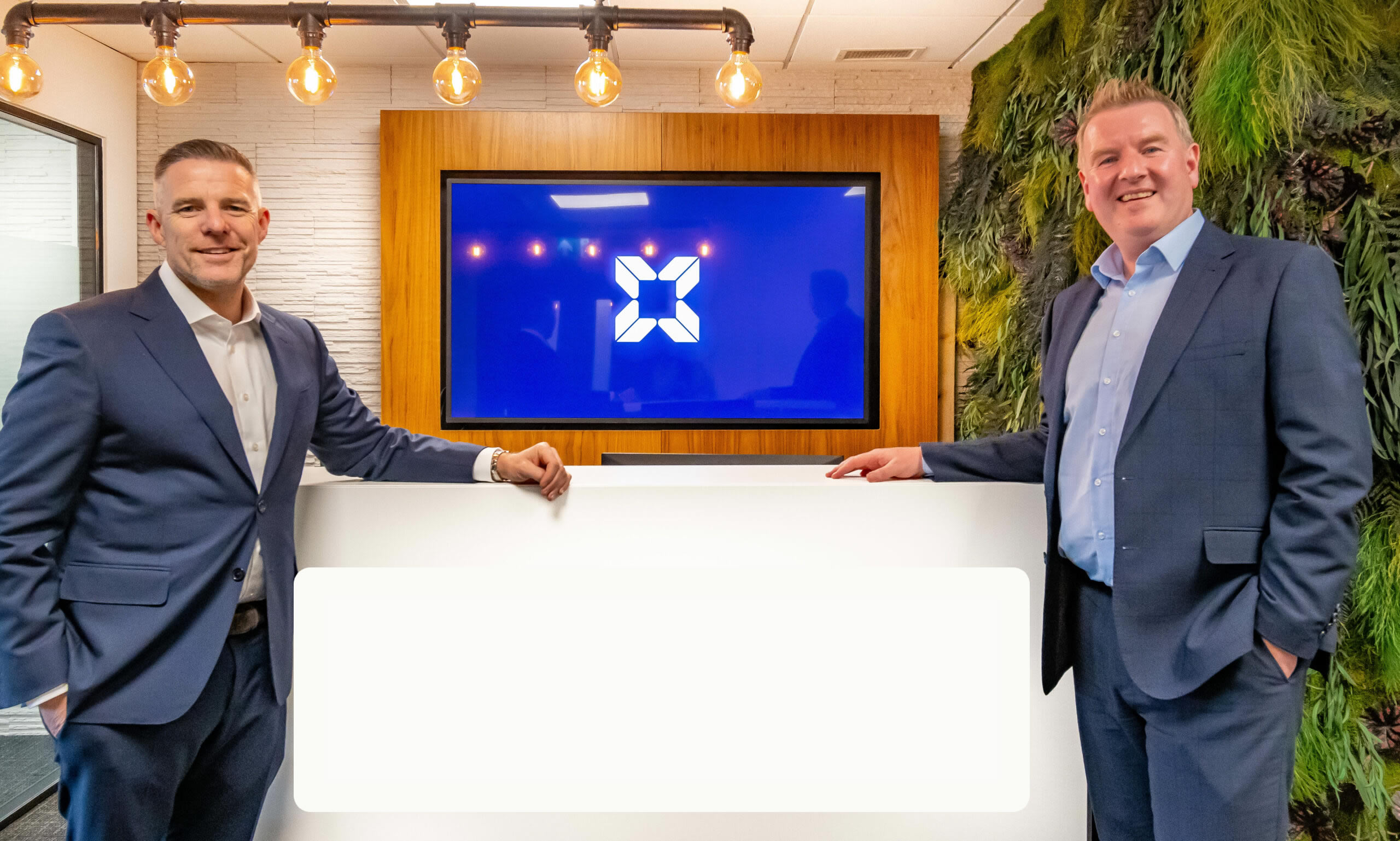 From left Leeds Corporate Finance CEO Paul Merriman & Conor Carey Leeds Corporate Finance Headford Director with the Leeds Corporate Finance logo background